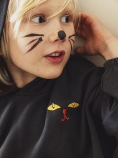 Close-up of a black cat ears hoodie showing cat face embroidery.