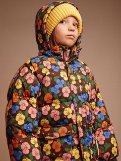 Yellow knitted ribbed hat worn with a floral puffer jacket.