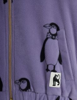 Close-up of a purple fleece jacket with a Penguin print, a gold-toned zipper, and a black panther logo patch.