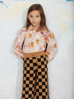 Brown and black chess check knitted trousers with a drawstring waist, worn by a child.