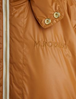Close-up of a beige puffer jacket featuring M.RODINI embroidery, a zipper closure, and gold-tone snap buttons.