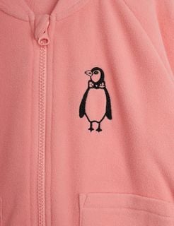 Close-up of a pink microfleece jacket showing a penguin embroidery and a zipper on the chest.