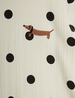 Close-up of off-white ribbed fabric featuring a black dot pattern and an embroidered brown dachshund.