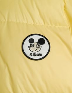 Close-up of a circular Ritzratz motif patch with M. RODINI text on a yellow puffer jacket.
