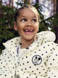 Close-up of an off-white heavy puffer jacket with black polka dots and a Ritzratz patch.