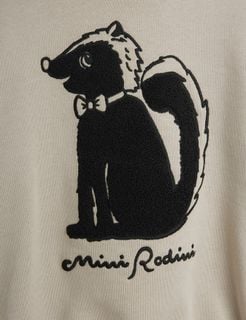 Close-up of the black skunk chenille artwork with a bow tie and script logo on grey fabric.