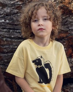 Yellow short-sleeved t-shirt featuring a black skunk print with a bow tie on the chest.