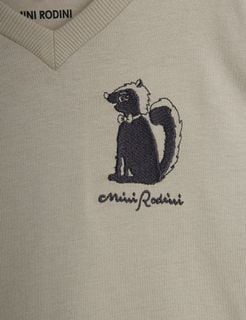 Close-up of a skunk embroidery and brand logo on a grey top.