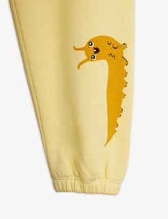 Close-up of yellow sweatpants leg featuring the Velvet worm print and a ribbed elastic ankle cuff.