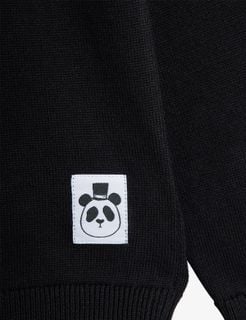 Black fine knit jumper detail featuring a white label with a panda wearing a top hat.
