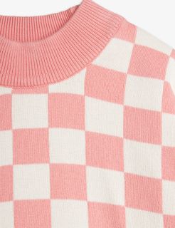 Close-up of a pink and white checkered knitted sweater with a ribbed neckline.