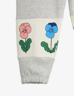 Close-up of a grey sweatpants leg featuring a white panel with pink and blue Violas print and elastic cuff.