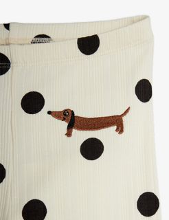 Close-up of off-white ribbed fabric with a black dots print and an embroidered brown dog motif.