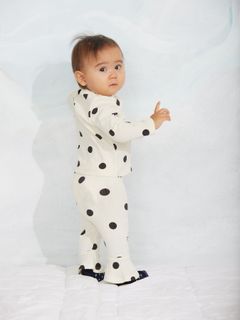 Off-white organic cotton flared trousers with a black Dots print, worn by a baby looking back.