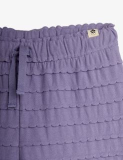 Close-up of purple trousers featuring horizontal frills with scalloped edges, drawstring waist, and a panda label.