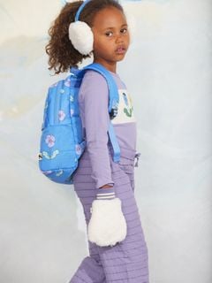 Purple textured frill trousers worn with a blue floral backpack and white fuzzy mittens.