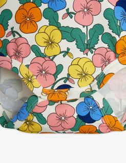 Close-up of a white bodysuit with a colorful Viola flower print and gold-tone snap buttons.