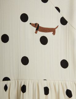 Close-up of an off-white ribbed dress with black polka dots and an embroidered dachshund dog.