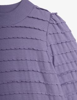 Close-up of a purple textured dress featuring layered horizontal scalloped frills across the chest and sleeves.
