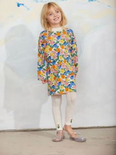 Long-sleeved dress featuring a colorful Viola flower print and a ribbed collar, worn with white patterned tights.