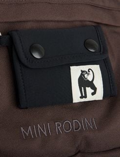 Close-up of a detachable black mini bag featuring a panther patch on a brown backpack with embroidered logo.