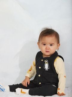 Black microfleece vest featuring a penguin patch and snap buttons, worn by a child.