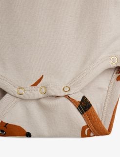 Gold-tone snap buttons at the crotch of a grey bodysuit with a brown dog print.