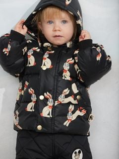 Black hooded puffer featuring a rabbit print and gold-colored snap buttons, worn by a child.