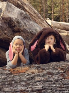 Brown faux-fur jacket with a rabbit-ear hood, worn by a child sitting outdoors.