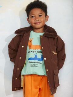 Brown padded nylon parka with faux fur collar and dachshund embroidery, worn by a child.