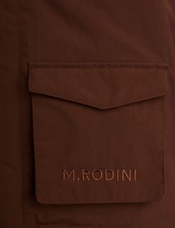 Detail of a brown padded parka showing a front pocket with tonal M.RODINI embroidery.