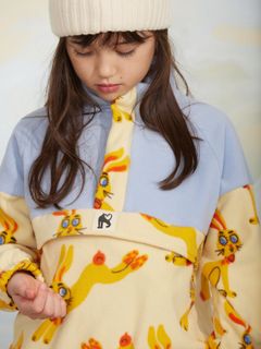 Close-up of a half-zip fleece sweater featuring a rabbit print and a chest pocket, worn by a child.