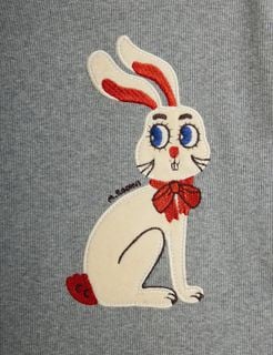 Cream rabbit application with a red bow and blue eyes on grey melange ribbed fabric.