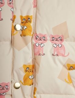 Close-up of the Kittens print on a light beige puffer jacket with gold snap buttons.