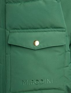 Close-up of a green puffer jacket pocket featuring a gold snap button and logo embroidery.