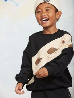 Black sweatshirt featuring an off-center beige panel with elephant shrew print, worn by a child.