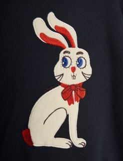 Close-up of a white rabbit application with a red bow on a black sweatshirt.