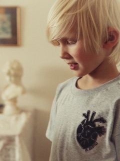 Close-up of a child wearing a grey melange t-shirt with a heart application on the chest.