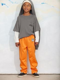 Grey long-sleeve top with chest pocket and white layered sleeves, worn by a child with orange trousers.
