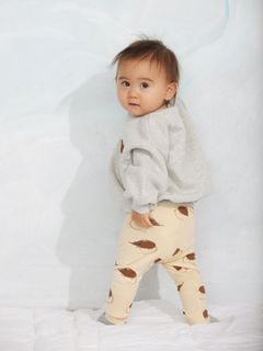 Beige leggings with elephant shrew print worn by a child looking over their shoulder.