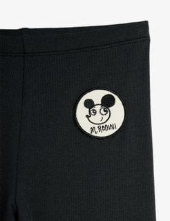 Black leggings close-up featuring a round white Ritzratz patch and an elastic waistband.