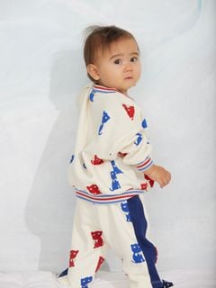 Off-white sweatpants with Kittens print and contrast side panels, worn by a child.