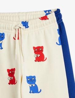 Off-white sweatpants with red and blue Kittens print, elastic drawstring waist and blue side panels.