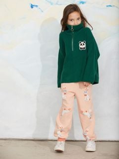 Green chunky knit half-zip sweater with a panda patch on the chest, worn by a child with patterned trousers.