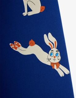 Leaping white Rabbit print with an orange bow tie on blue sweatpants, close-up.