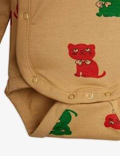 Beige wrap bodysuit detail featuring gold snap buttons and red and green Kittens print.