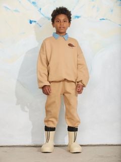 Beige sweatshirt and matching sweatpants with an elephant shrew embroidery, worn by a child.