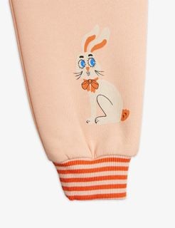 Pink sweatpants featuring a white Rabbit print and orange and white striped ribbed cuffs.