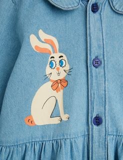 Close-up of the Rabbit print with an orange bow and dark blue buttons on a blue denim dress.