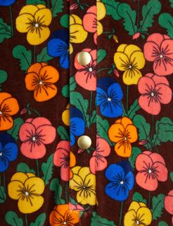 Colorful Violas print on brown velour bodysuit featuring gold snap buttons, close-up.